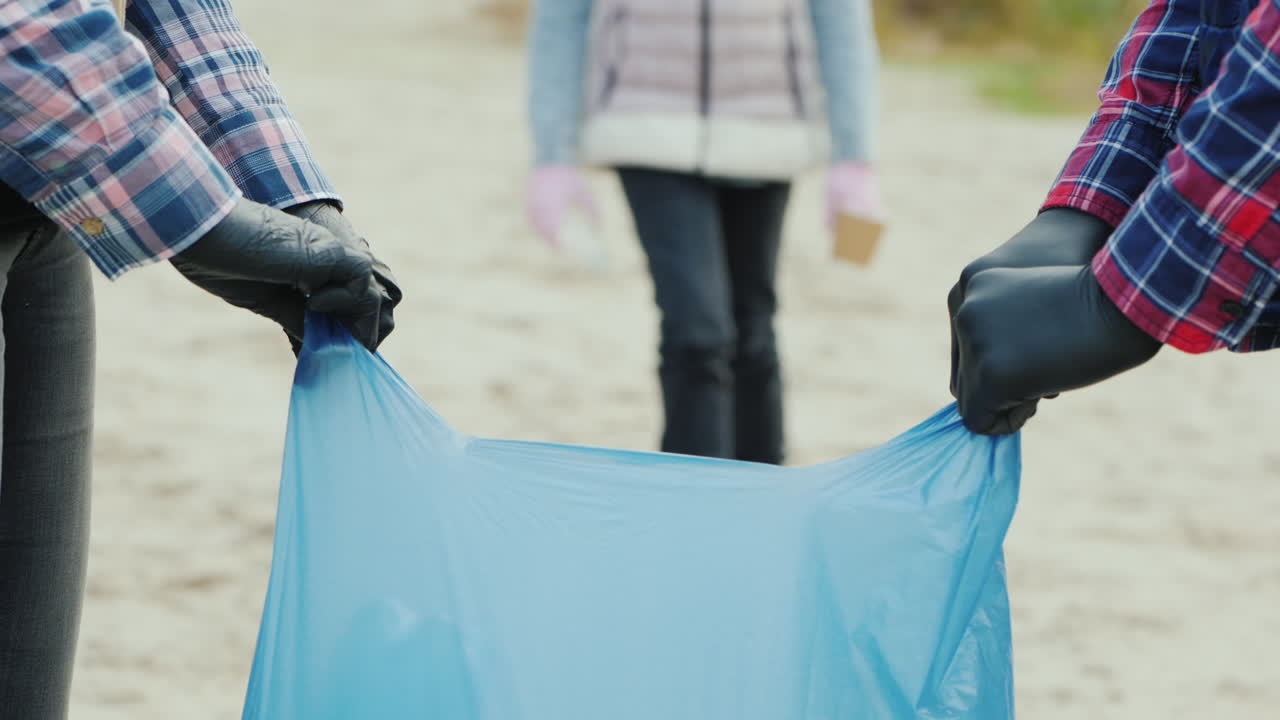 어린이 자원 봉사자가 카메라를 보고 미소를 지으며 공원에서 쓰레기를 수거합니다.