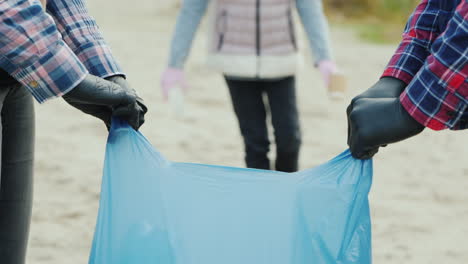 child volunteer collects trash in the park smiling at the camera