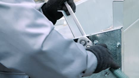 man in fabric gloves tightening nuts on bolts with universal wrench