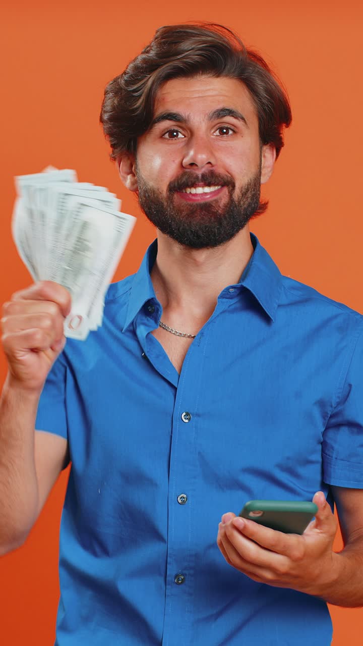 Young man use smartphone rejoicing win receiving money dollar cash banknotes celebrating success