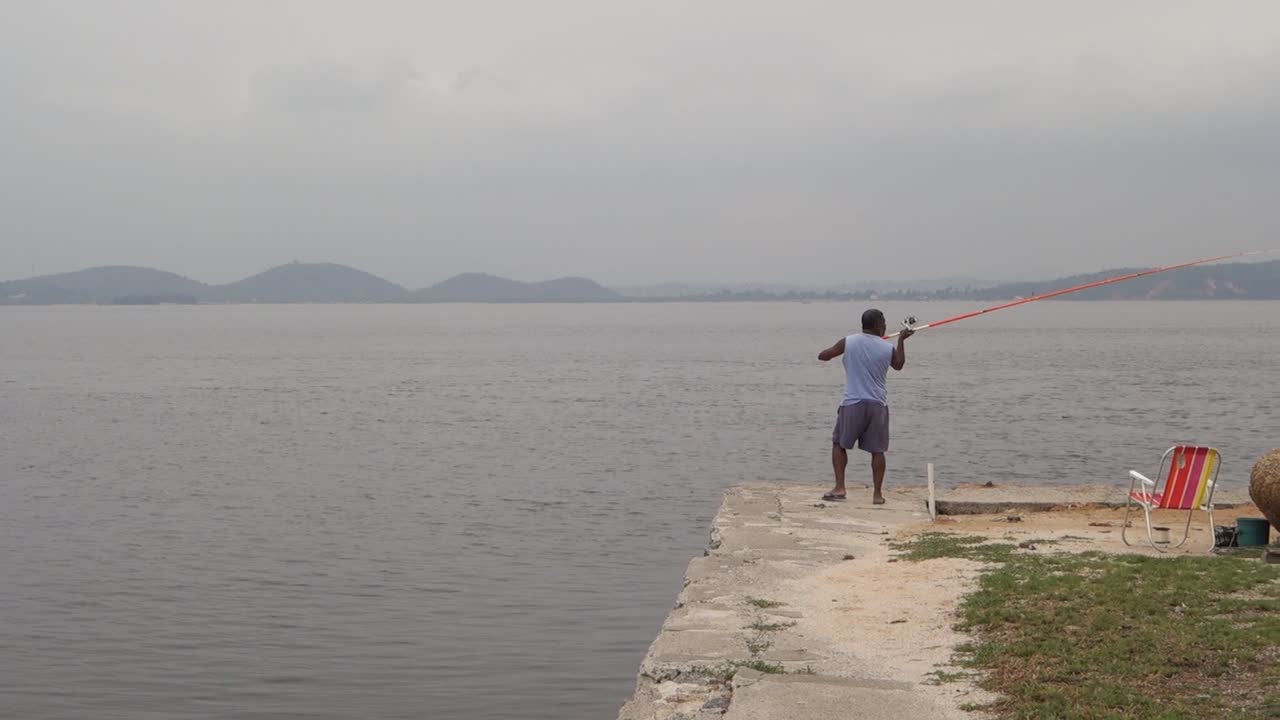 Local Man Throws Fishing Rod With Bait In The Water. - wide shot
