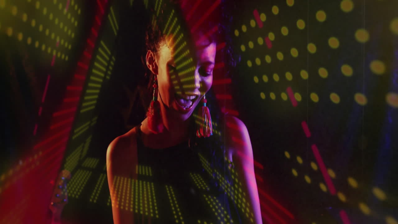 Woman standing in dark studio, using projecting green yellow red geometry for tech branding