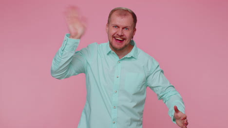 bearded man smiling friendly at camera and waving hands gesturing hello or goodbye, welcoming