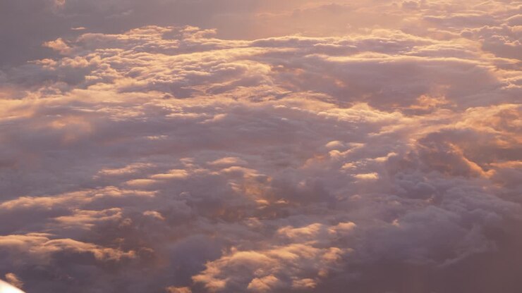 Cloudscape through airplane window. Sunset time. Aerial view
