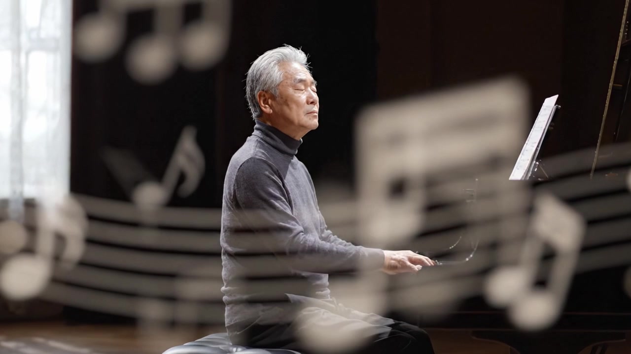 An accomplished pianist deeply immersed in his performance, showcasing emotion and skill as he plays beautifully onstage amidst soft natural lighting.