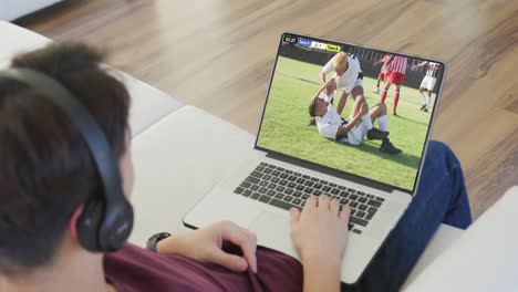 Video-Einer-Person,-Die-Auf-Der-Couch-Sitzt-Und-Sich-Ein-Fußballspiel-Auf-Dem-Laptop-Ansieht