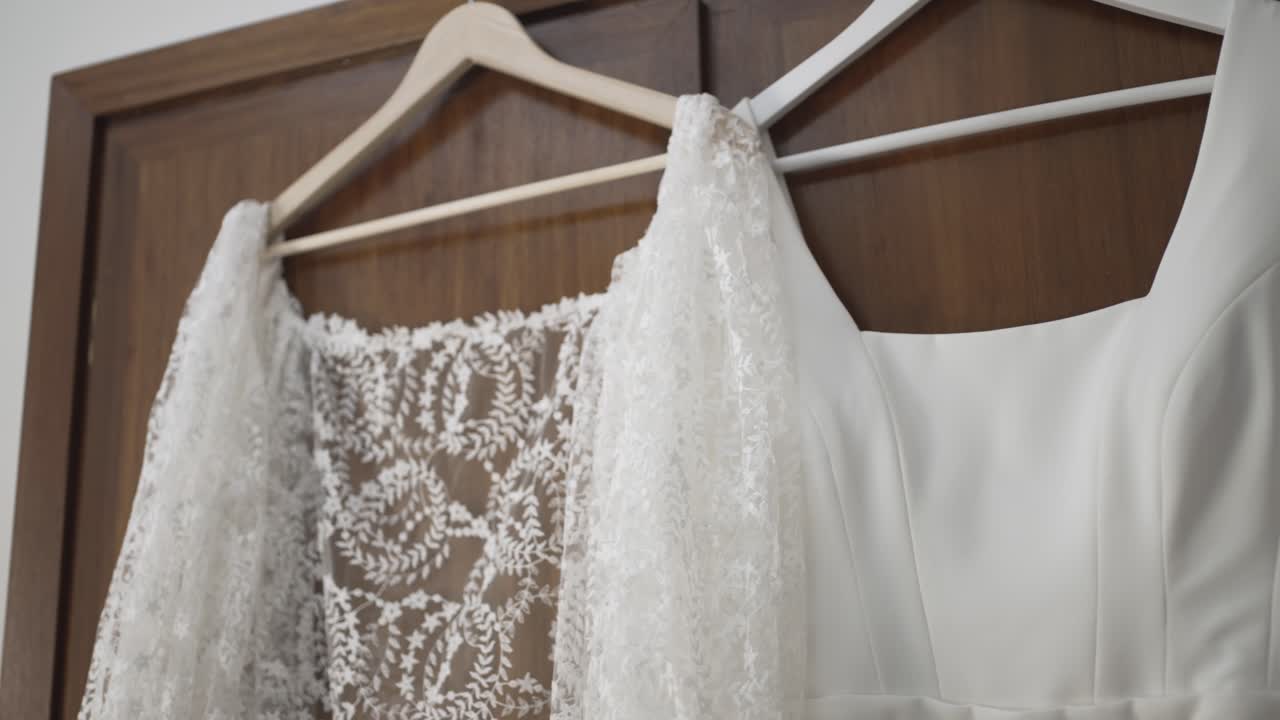 Close up of white wedding dress with intricate lace back hanging on wooden hanger