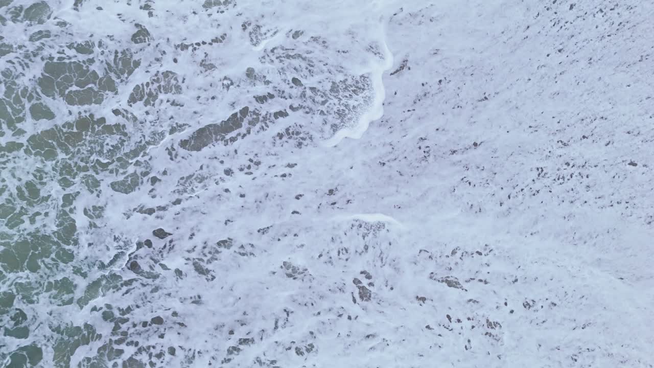 Ocean whitewash waves crash on sandy beach barreling and foaming as water recedes