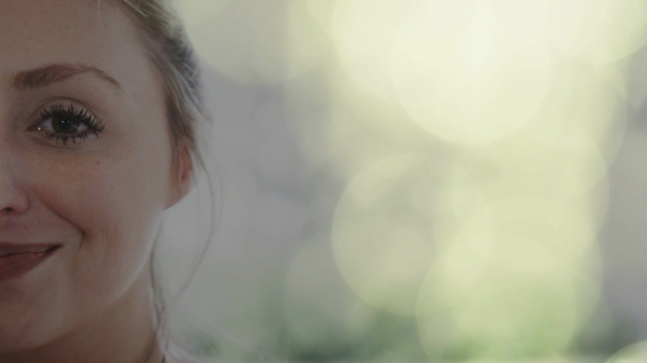 Donna sorridente con occhio aperto e banda bokeh verticale animata luminosa, che crea un focus per un annuncio di bellezza