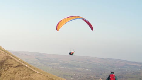 Paraglider-Flying-Close-Over-Hikers,-Turning-And-Soaring-On-Thermals