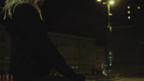 Woman-sitting-night-city-enjoying-view-of-street-lights-in-urban-area.