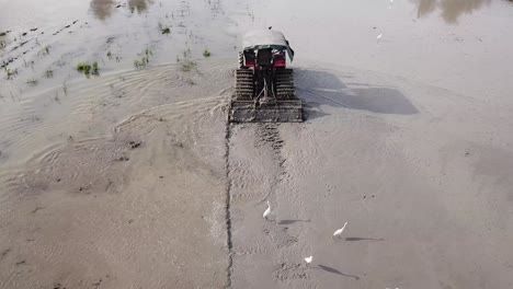 Tractor-plough-soil-rice-paddy,-agriculture-in-Malaysia.