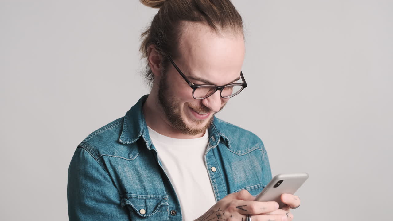 Caucasian young man texting on smartphone on camera.