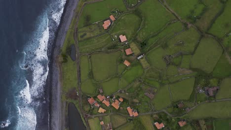 top down panorama view of a coastal village lush green landscape, fajã de santo cristo, são jorge island, the azores, portugal