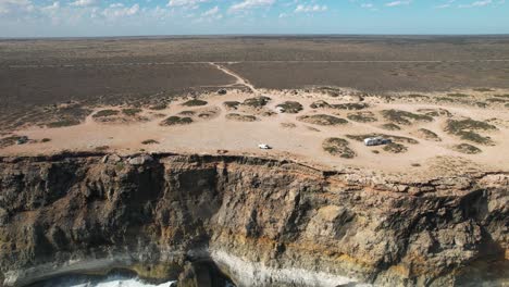 Disparo-De-Drone-Volando-Hacia-Altos-Acantilados-Con-Las-Olas-Rompiendo-Debajo