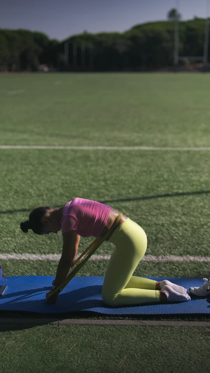 Donna che si allena con una fascia di resistenza su un campo sportivo