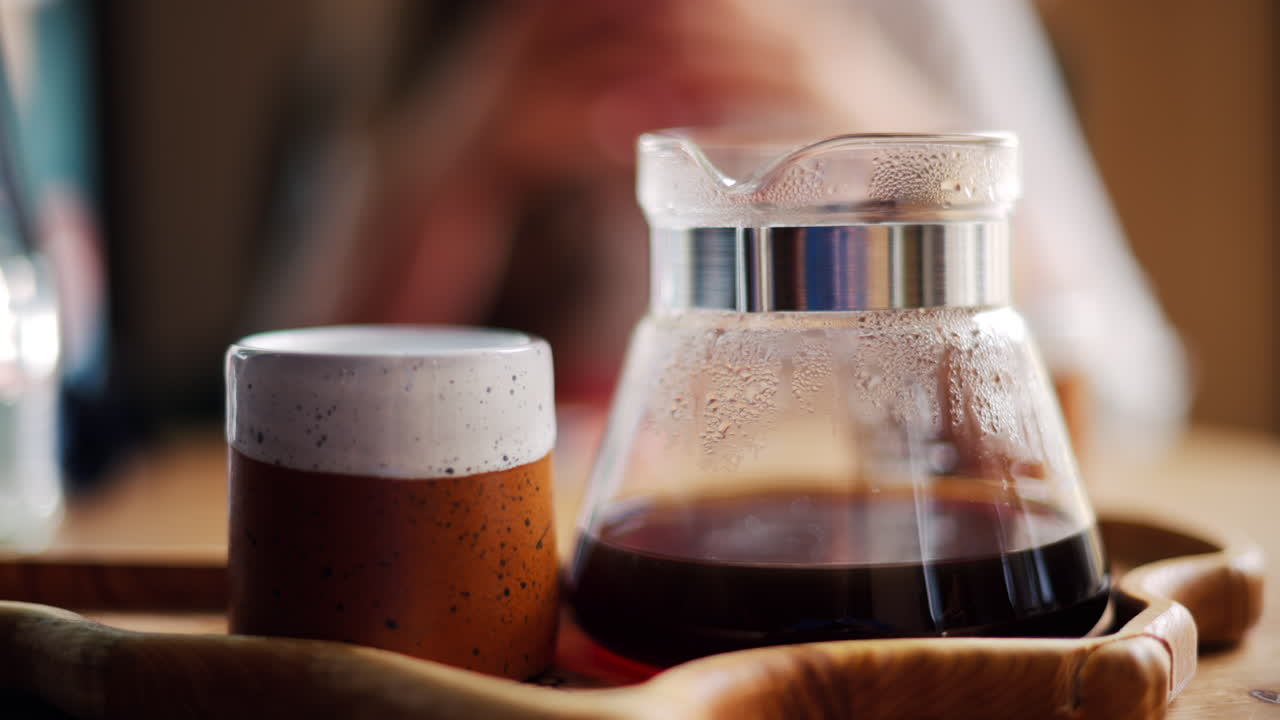 Close up of a glass coffee pot and a cup standing on a wooden tray