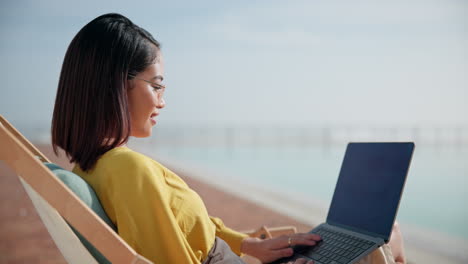 woman working on laptop at the beach