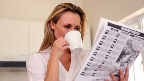 Mujer-Feliz-Leyendo-El-Periódico-En-El-Desayuno