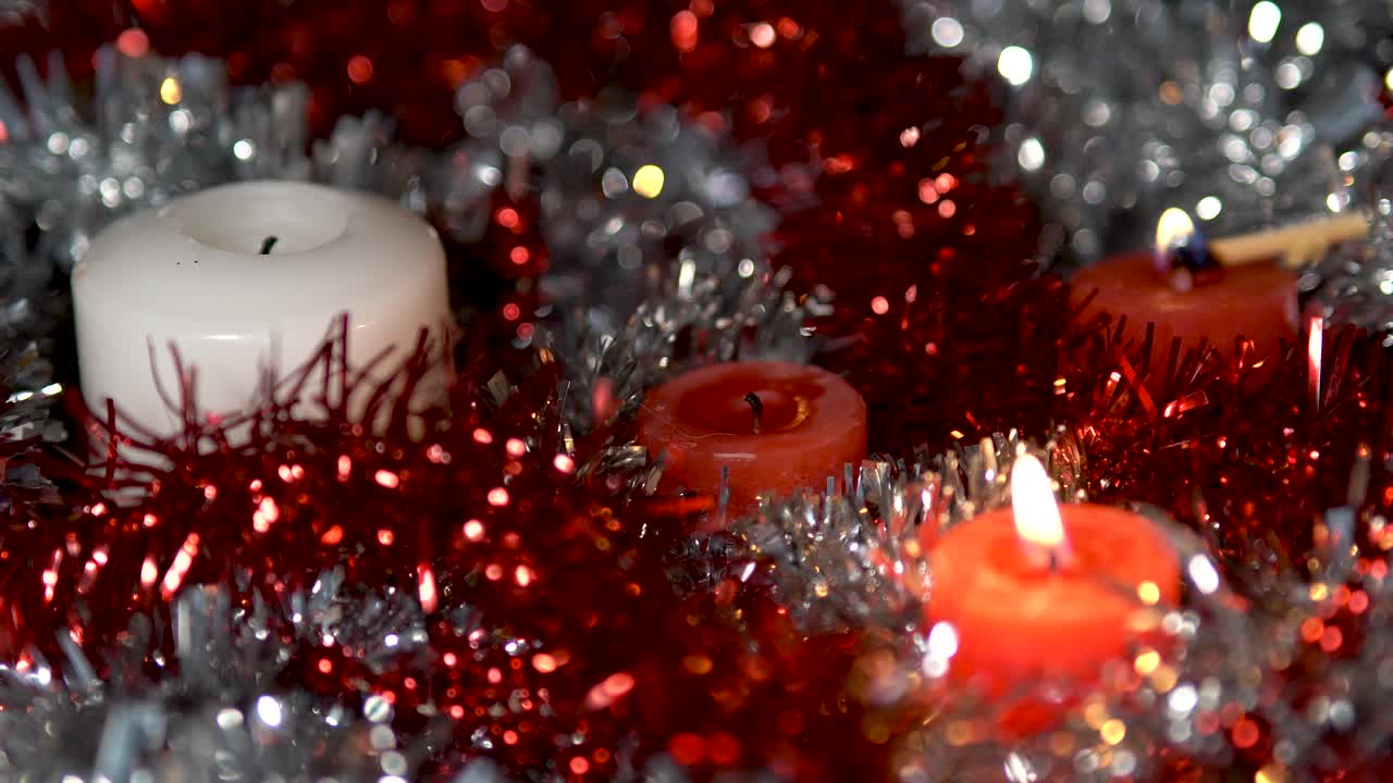 velas navideñas encendidas y apagadas, plata brillante y fondo rojo