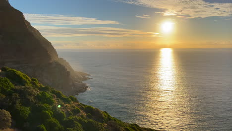 Chapman-Peak-Drive-sunset-horizon-light-Noordhoek-Hout-Bay-Marina-scenic-Table-Mountain-epic-travel-road-coastline-cliffside-view-Cape-of-Good-Hope-South-Africa-lush-summer-cinematic-pan-left-slowly