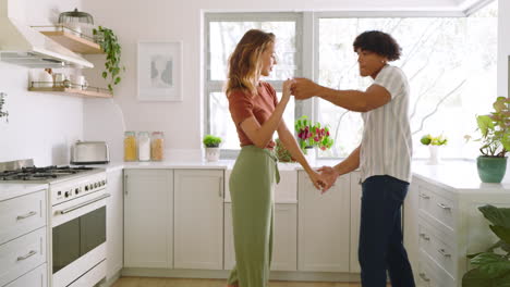 happy diverse couple dancing together in bright kitchen, enjoying morning routine, at home