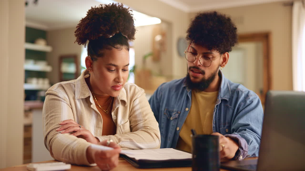 pareja mirando el papeleo y una computadora portátil mientras sonríen