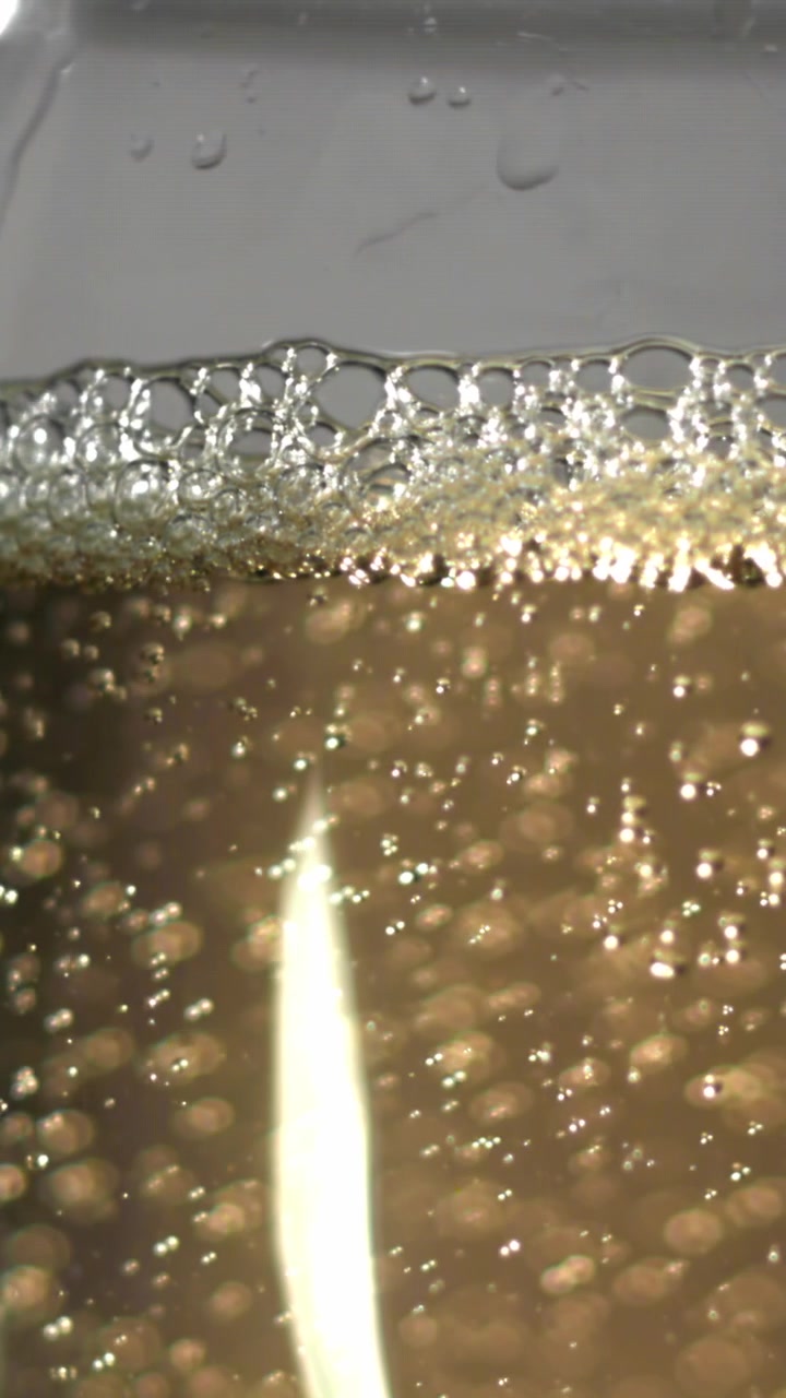 Primer plano de líquido dorado brillante con burbujas ascendentes