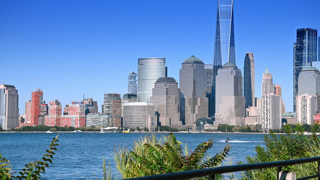 Waterfront walk with skyline views. People stroll along the waterfront pathway enjoying the vibrant skyline in New York during a sunny day