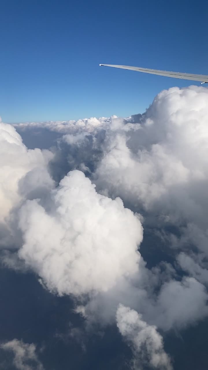 Filmato verticale da telefono di nuvole bianche super soffici e un cielo blu visti da un volo.