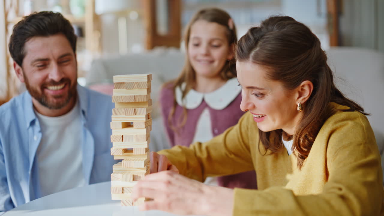Una famiglia felice gioca insieme costruendo una torre con dei blocchi in un soggiorno accogliente