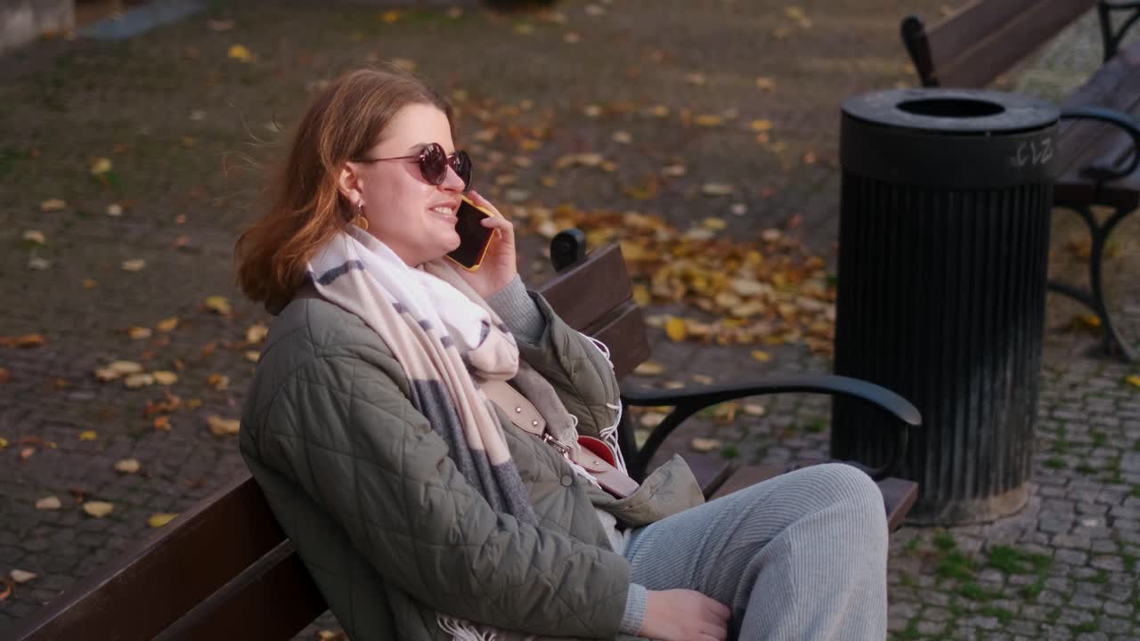 Kvinde taler i telefon i efterårspark