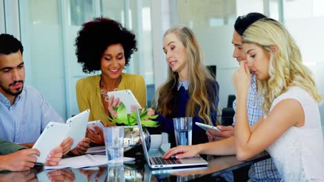 Colleagues-using-electronic-gadgets-at-table-4k