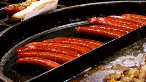 street food. sausage for hot dogs frying on a large skillet