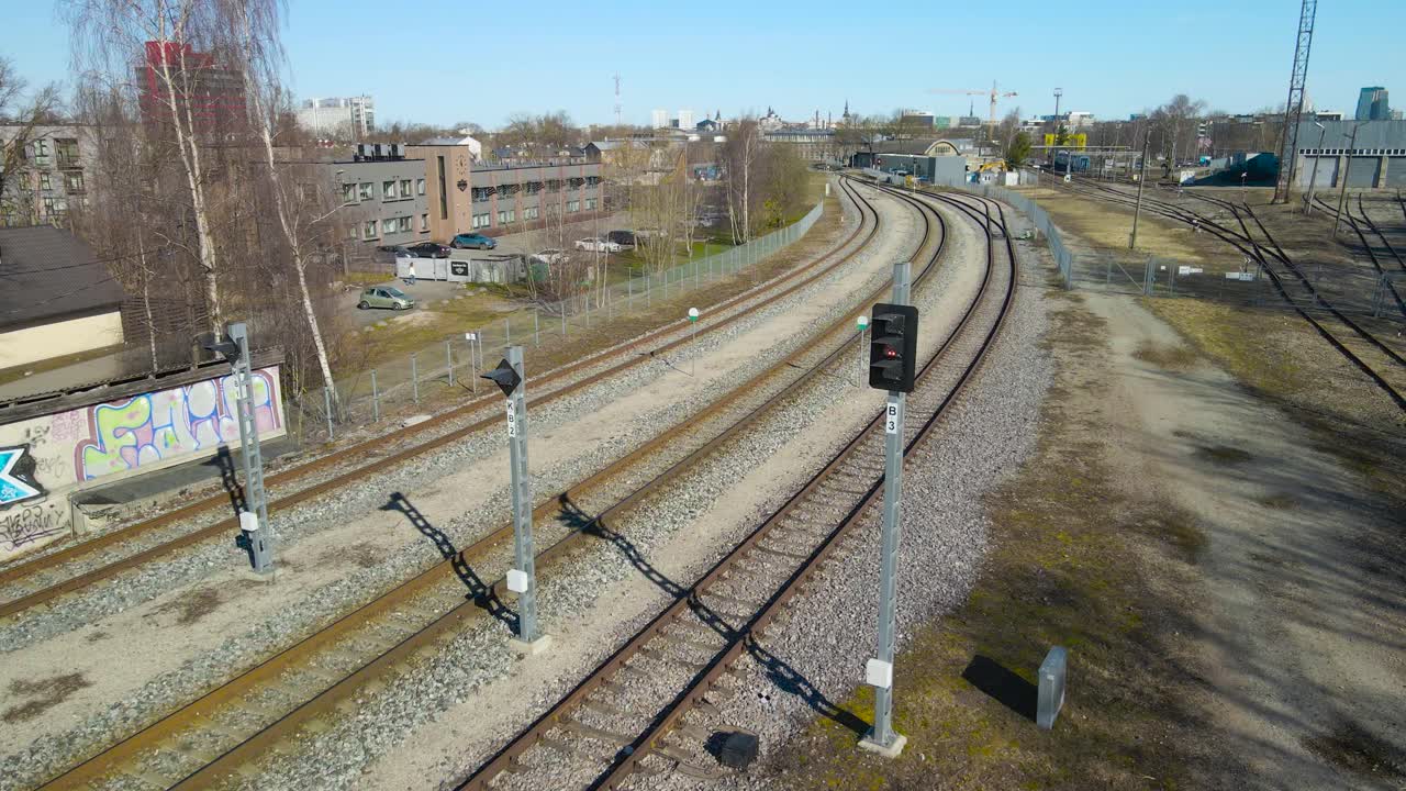 Aerial drone view slowly spinning and orbiting around a old vintage and retro traffic light besides a railroad or traintracks in Tallin väike station in Estonia Europe. Tallinn city is visible too.