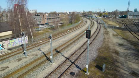aerial drone view slowly spinning and orbiting around a old vintage and retro traffic light besides a railroad or traintracks in tallin väike station in estonia europe. tallinn city is visible too.