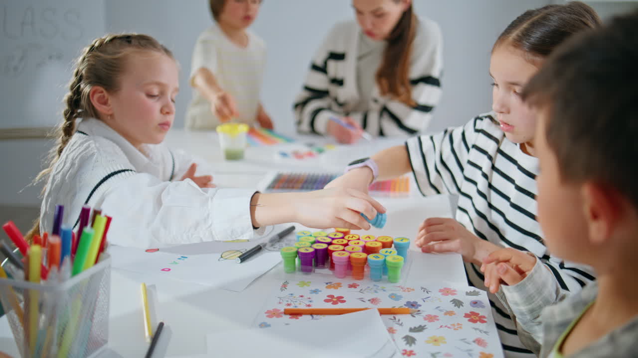 Focused kids playing stamps in school classroom closeup. Small pupils creating