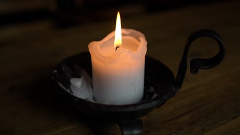Candle-in-a-candlestick-on-a-wooden-table