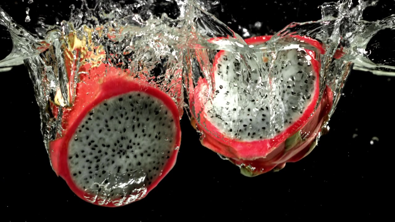 Lebendige Drachenfrucht-Hälften spritzen in klares Wasser