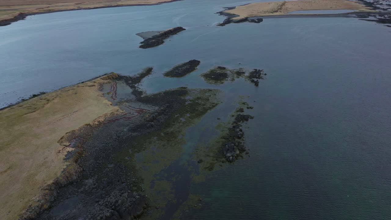 vista aérea de pequeñas islas frente a la costa de akranes en islandia, rodeadas de aguas tranquilas del océano y costas escarpadas