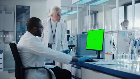 laboratorio de investigación médica moderno: dos científicos usan una computadora con pantalla clave de croma verde, los especialistas discuten tecnología innovadora. laboratorio científico avanzado para medicina, biotecnología