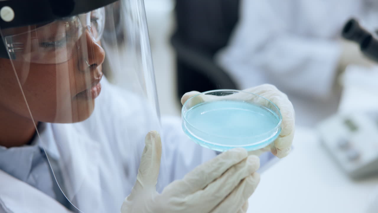 Scientist Examining Petri Dish with Blue Liquid in Laboratory