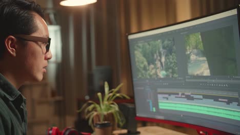 asian male video editor works with footage and sound on his personal computer, he works late at night