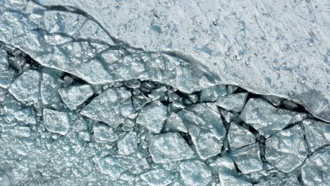 aerial top down, cracked polar ice sheet path caused by icebreaker ship