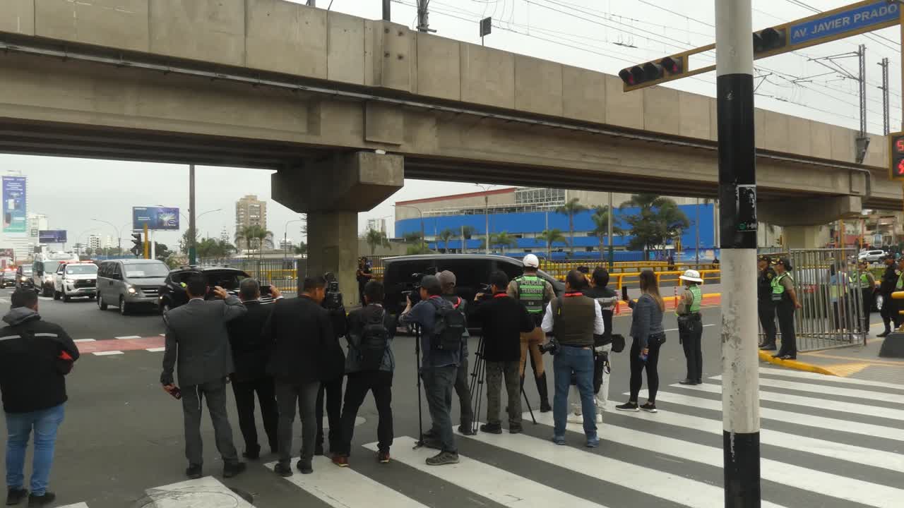 A Police motorcade drives by a group of reporters and cameramen and some police officers, as a part of the APEC 2024 summit in Lima, Peru.