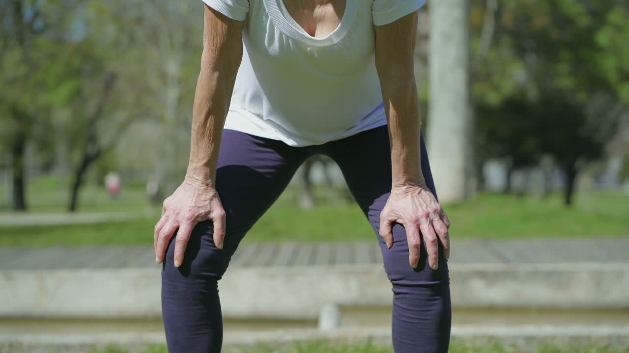 Gambe di donna di mezza età in piedi, piegate in avanti, che si riposano.