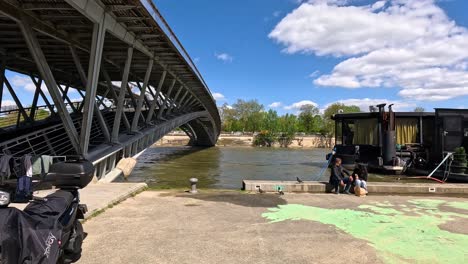 two people interacting near a river and bridge