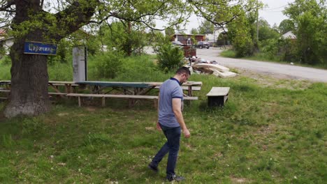 panning from the left to the right on a tourist walking in front of a tree, a natural landmark in the village of tsarichina in bulgaria