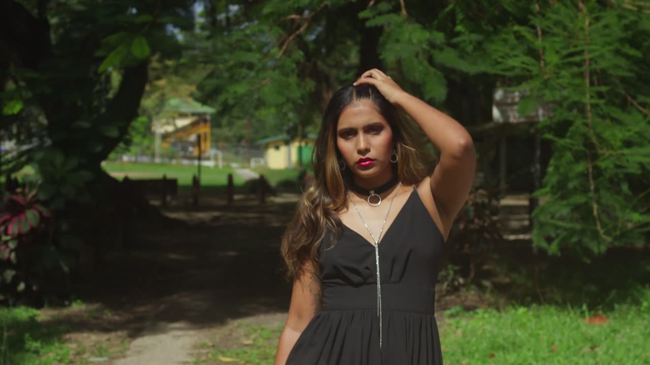 A young girl in a black dress relaxes by the peaceful river.