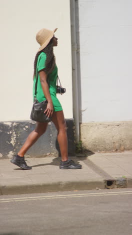 vertical video of female tourist with camera on vacation in oxford uk exploring city walking along holywell street